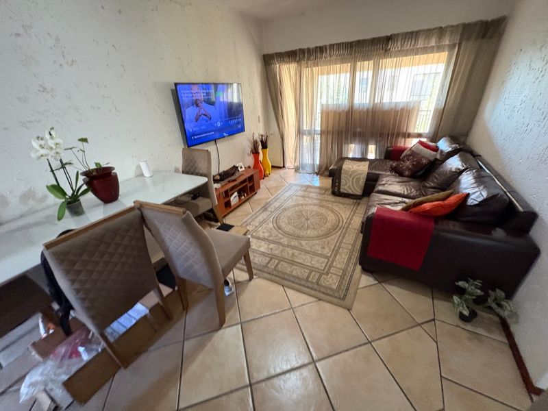 A living room featuring tiled flooring and a sliding glass door leading to an outdoor area, with visible wall surface wear requiring maintenance.