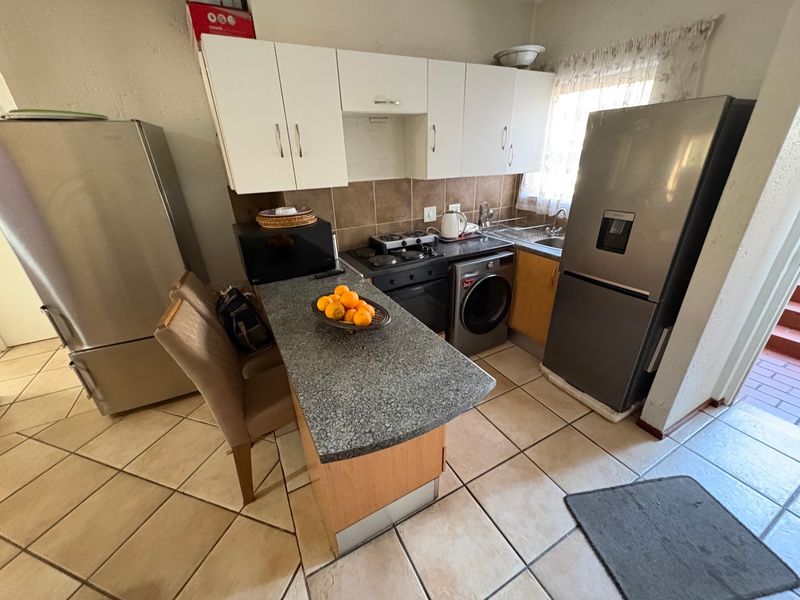 Compact kitchen featuring built-in cabinetry, granite countertops, a hob, oven, and tiled flooring, offering a functional layout for daily meal preparation.