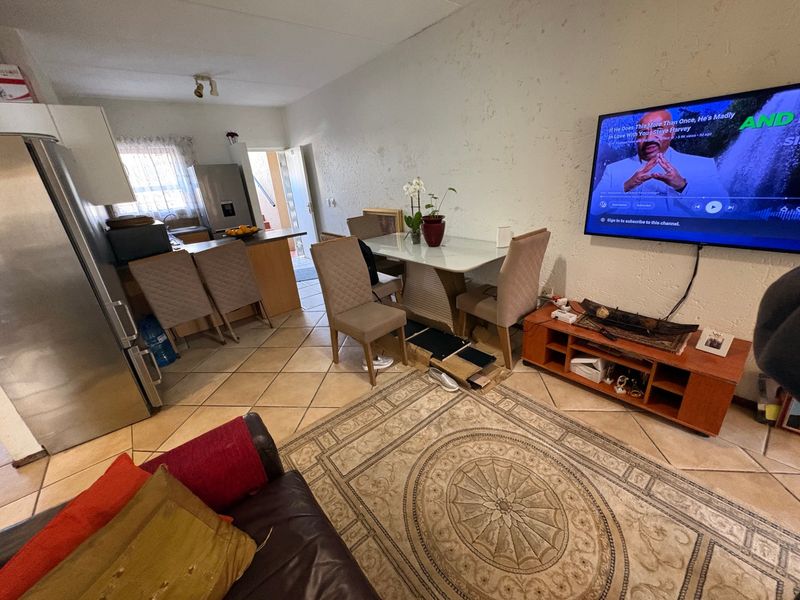 Open-plan living and dining area featuring tiled flooring and a compact kitchen space with built-in cabinetry.