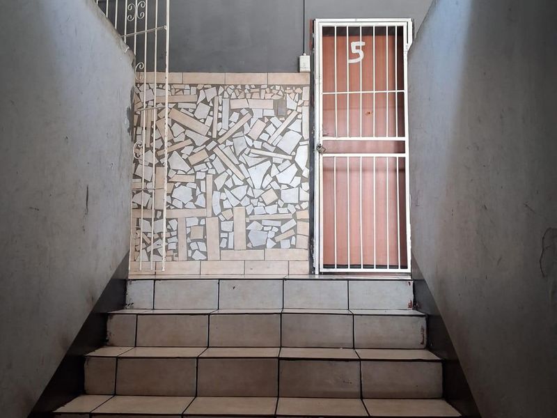 Entrance area featuring a tiled staircase leading to a secure unit door with a decorative mosaic wall accent.