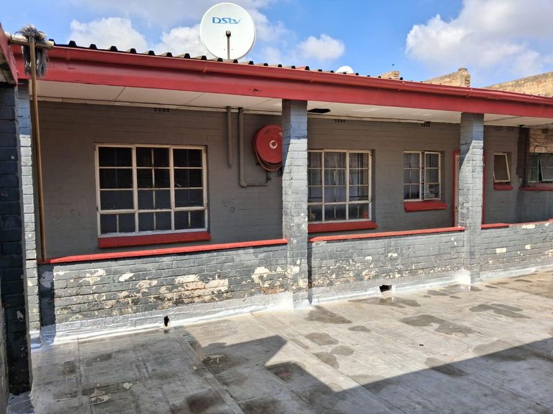 Exterior rear view of a commercial building featuring a concrete patio, brick masonry walls, steel windows, and a mounted fire hose reel.