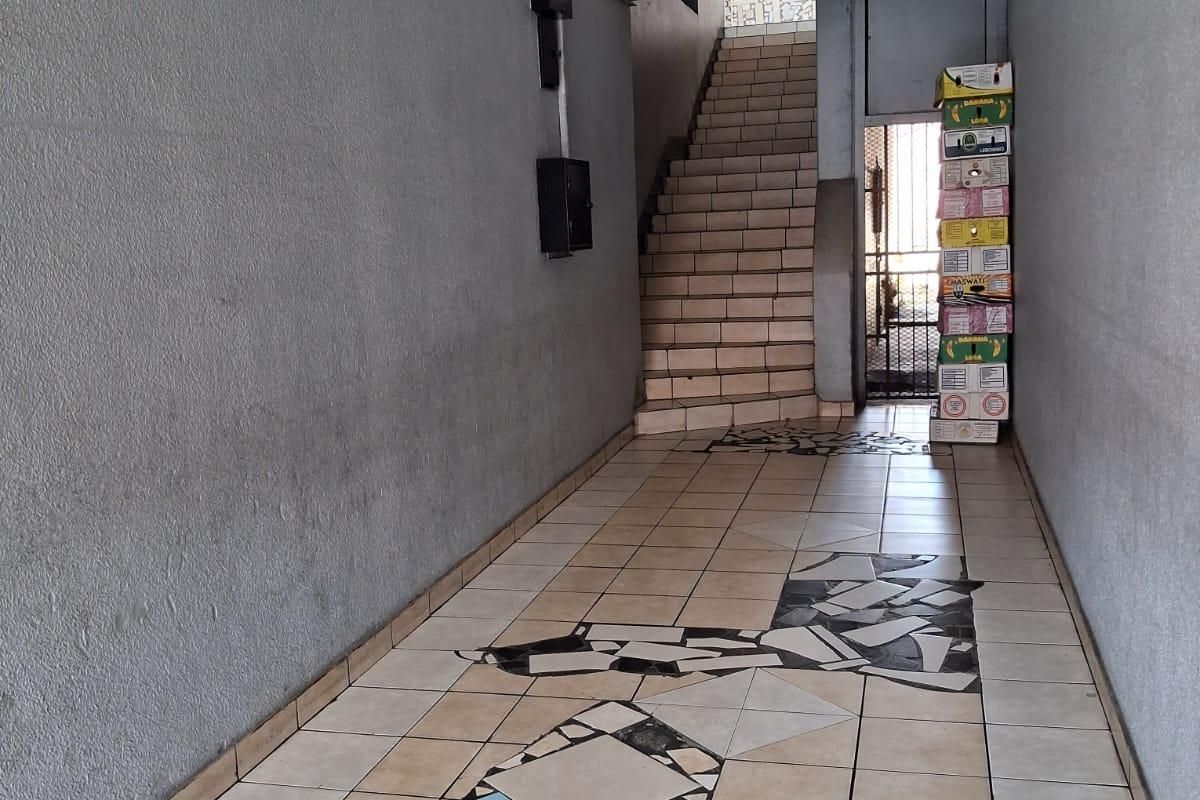 A commercial hallway featuring tiled flooring with decorative inlays, leading to a staircase and a secure metal gate entrance.