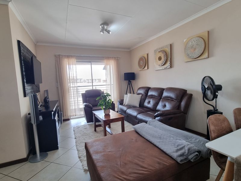 Open plan living area featuring tiled flooring, coved ceilings, and a sliding glass door providing access to the exterior.