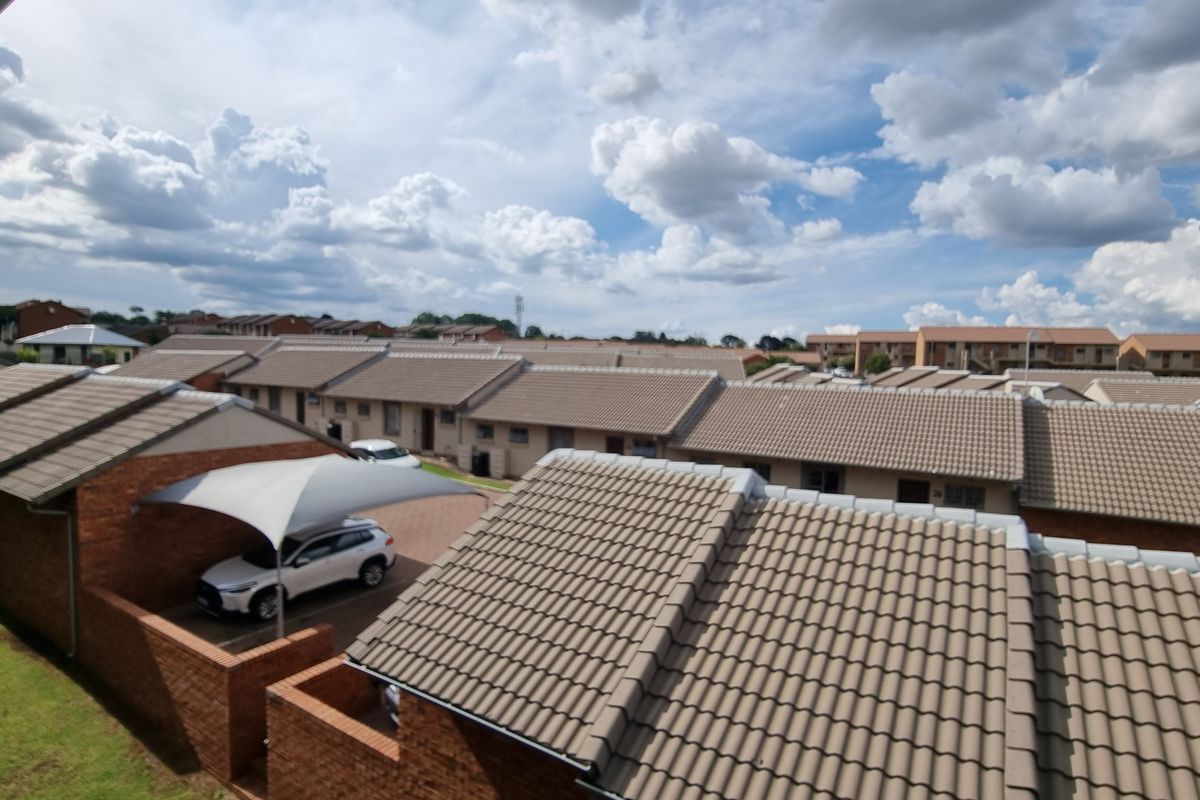 An elevated aerial view of a residential apartment complex featuring uniform tiled roofs, brick exterior walls, and a covered carport area.
