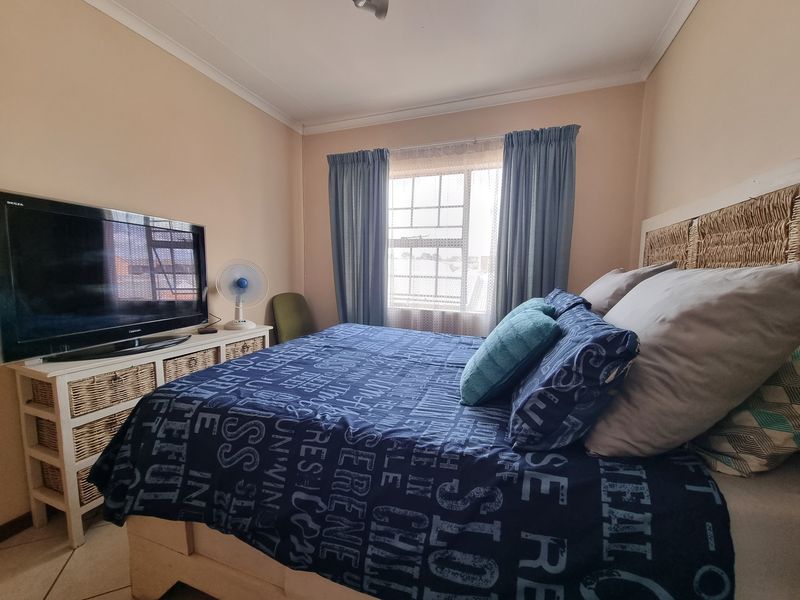 A functional bedroom featuring tiled flooring, a window with security bars, and coved ceiling detailing.
