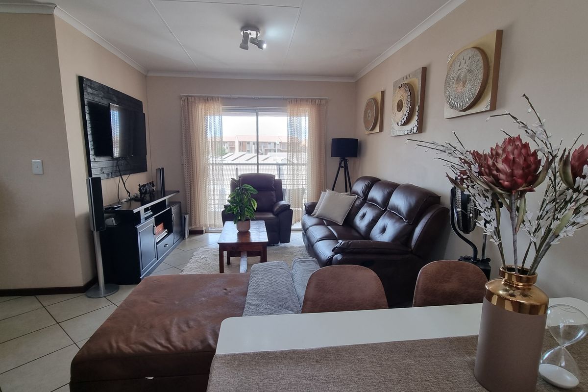 A comfortable living room featuring tiled flooring and a sliding glass door that provides natural light and access to the exterior.