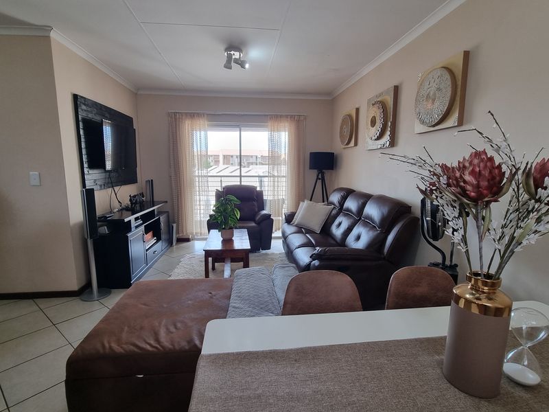 A comfortable living room featuring tiled flooring and a sliding glass door that provides natural light and access to the exterior.