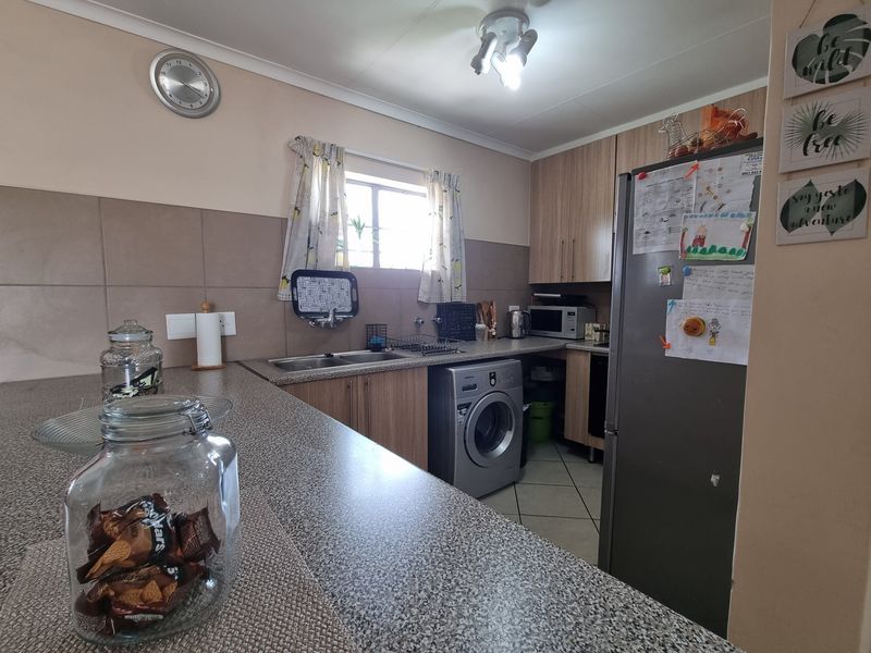 Functional kitchen featuring laminate cabinetry, granite-look countertops, a double bowl sink, tiled backsplash, and dedicated space for a washing machine.