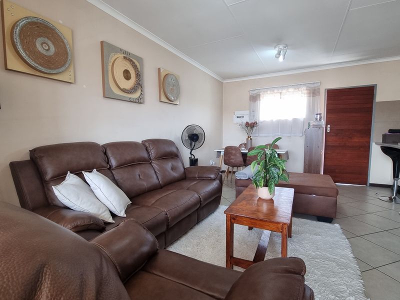 Open plan living and dining area featuring tiled flooring and a timber entrance door, providing a functional and connected living space.