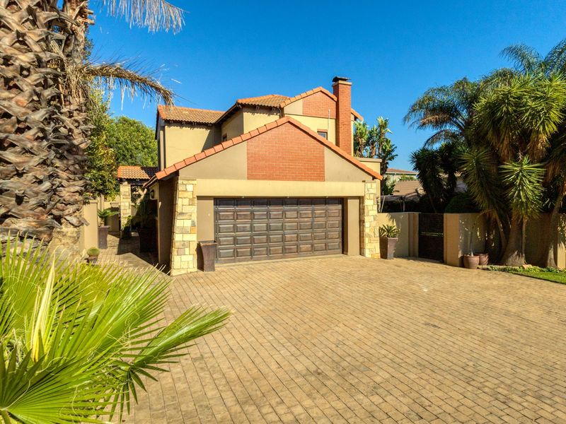 Front view of a double-story residential property featuring a paved driveway, double garage, and attractive stone and brick exterior detailing.