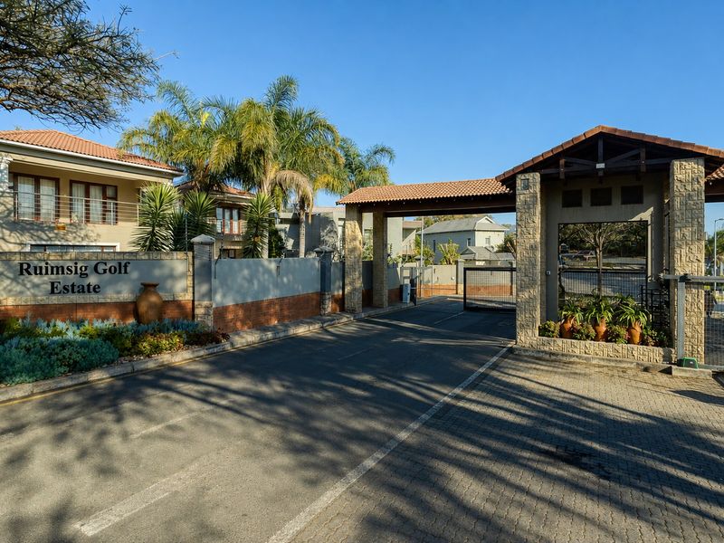 The entrance gate and security access point for Ruimsig Golf Estate, featuring stone-clad pillars, tiled roofing, and paved driveway access.