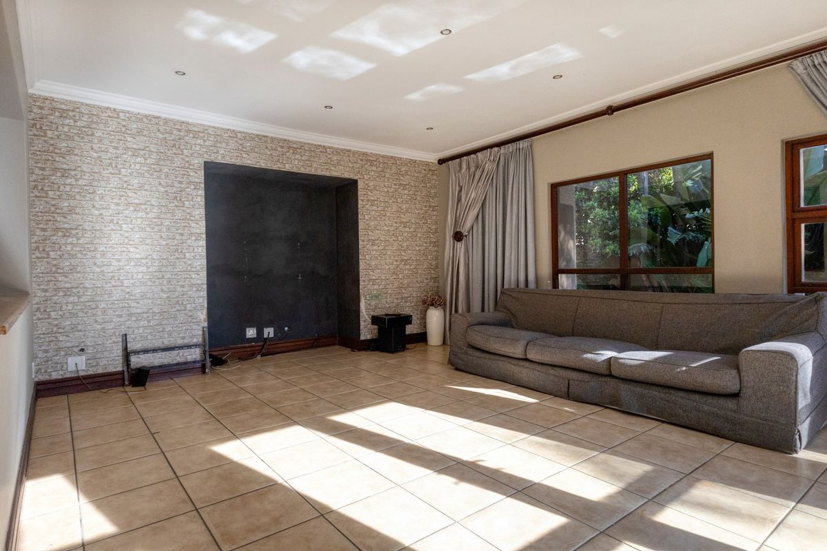 Spacious living room featuring tiled flooring, a textured feature wall with a built-in media alcove, and large windows allowing for natural light.