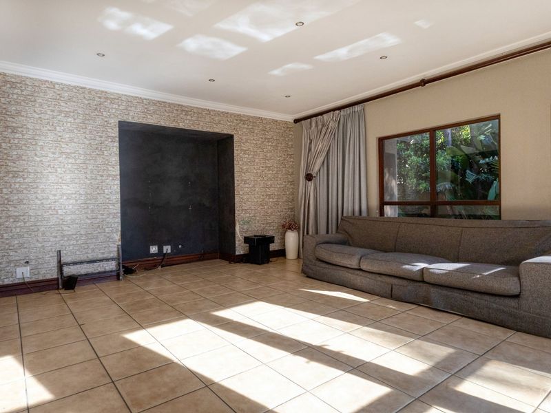 Spacious living room featuring tiled flooring, a textured feature wall with a built-in media alcove, and large windows allowing for natural light.