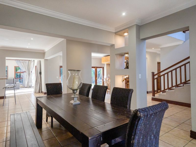 Spacious open-plan living area featuring tiled floors, recessed display shelving, and a wooden staircase, creating a bright and well-connected interior layout.