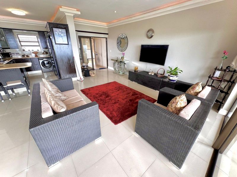 Spacious open-plan living area featuring tiled floors, recessed ceiling lighting, and a modern kitchen with built-in cabinetry and integrated appliances.