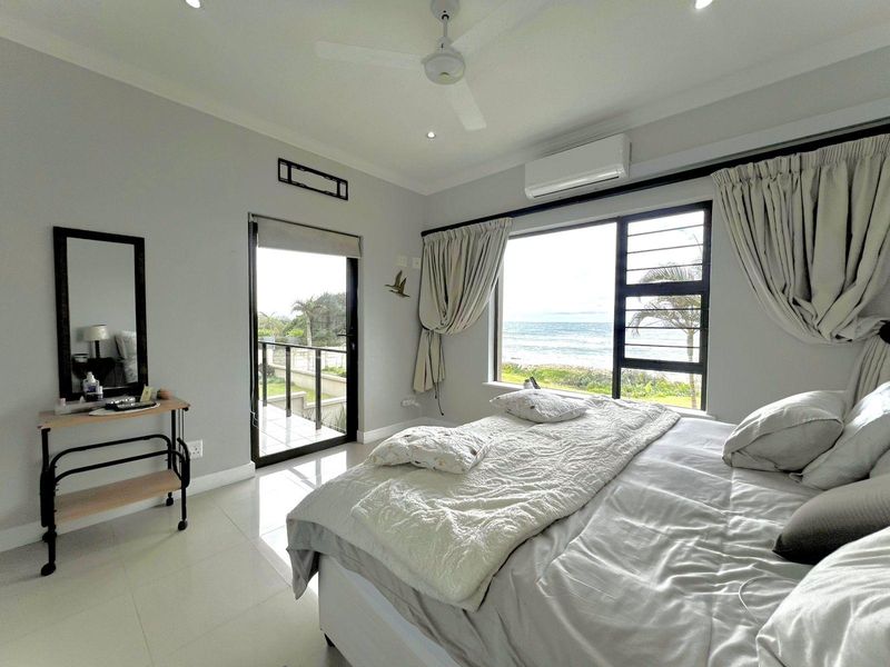 A bright bedroom featuring tiled floors, a ceiling fan, air conditioning, and direct access to a balcony with scenic ocean views.