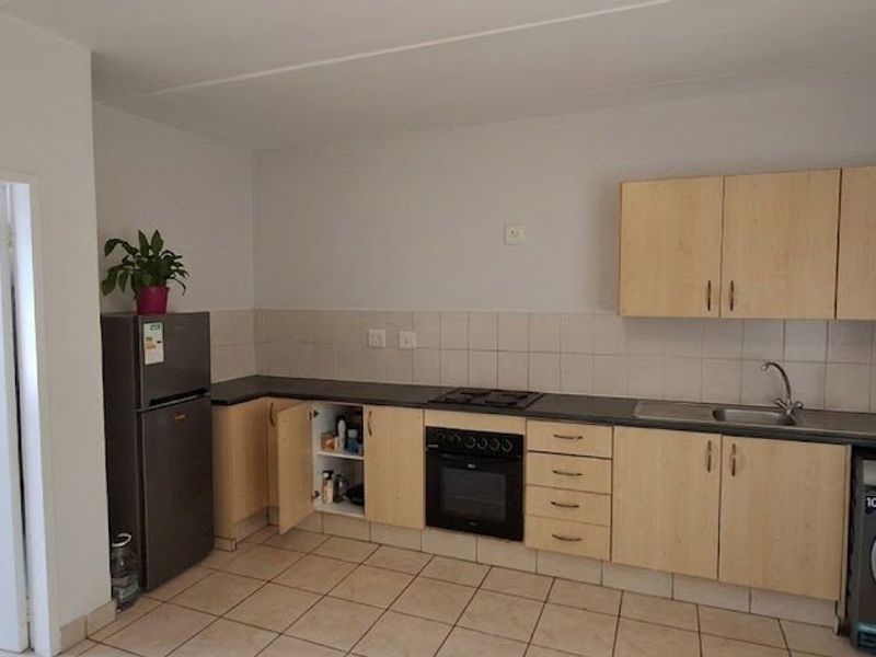 A functional kitchen featuring light wood-tone cabinetry, dark laminate countertops, a built-in oven with gas hob, and tiled flooring.