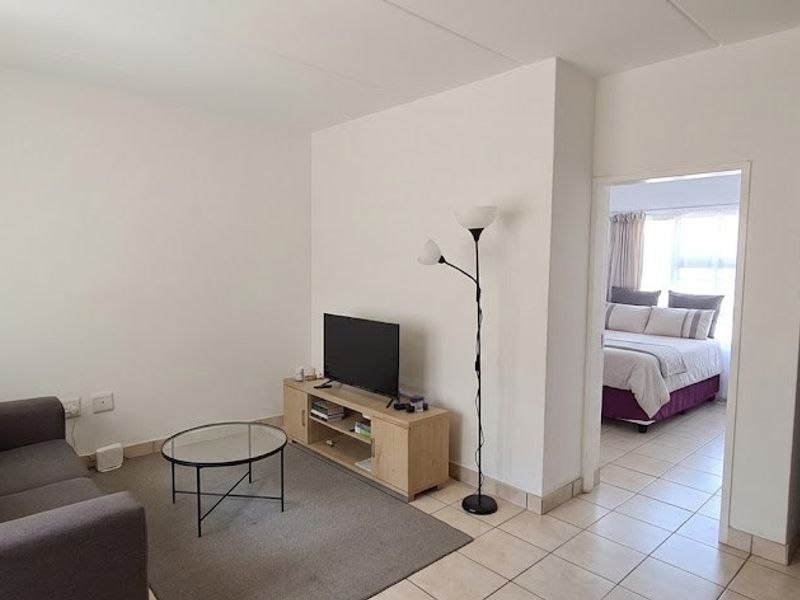 Open plan living area with tiled flooring, leading directly into the adjacent bedroom space.