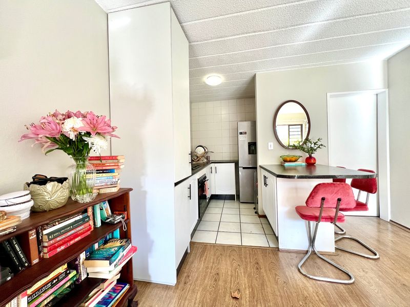 Open-plan kitchen and living area featuring a breakfast bar, white cabinetry, tiled kitchen flooring, and laminate wood flooring in the living space.