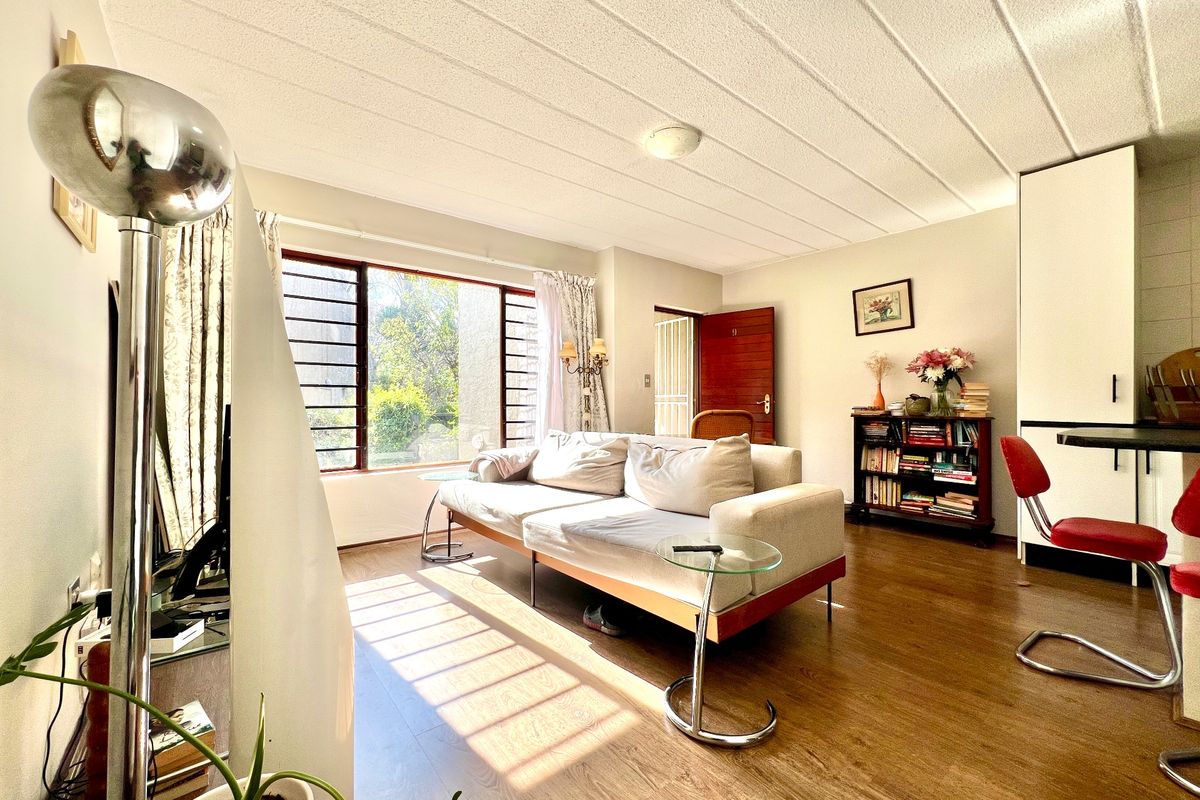 Bright living room featuring laminate flooring, a textured ceiling, and large windows allowing for ample natural light.