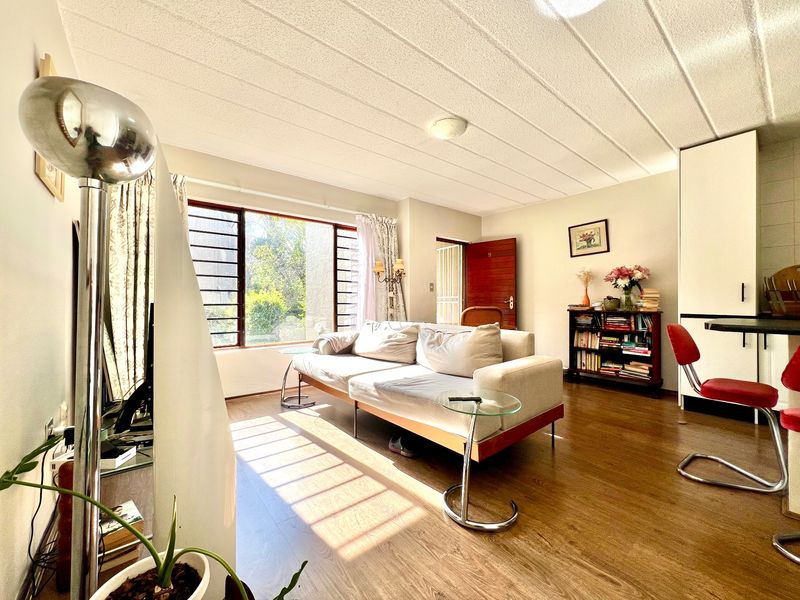 Bright living room featuring laminate flooring, a textured ceiling, and large windows allowing for ample natural light.