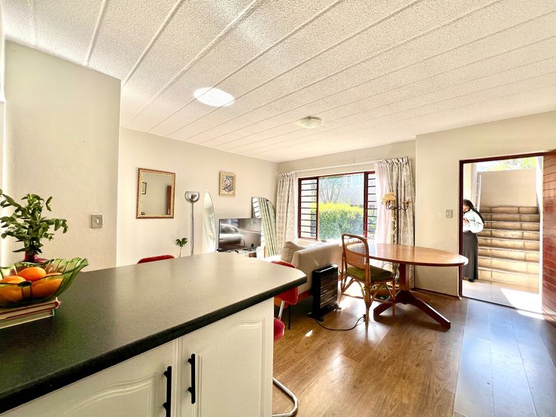 Open-plan living and kitchen area featuring laminate flooring, textured ceilings, and direct access to an external staircase.