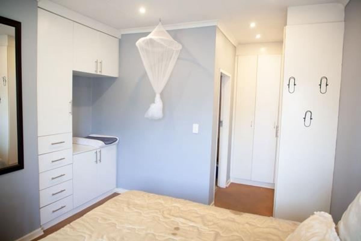 A well-maintained bedroom featuring extensive white built-in cabinetry, recessed ceiling lighting, and neutral wall finishes.