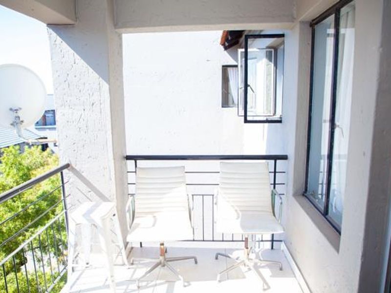 A covered balcony featuring tiled flooring, metal safety railings, and casement windows, providing an outdoor space with views of the surrounding area.