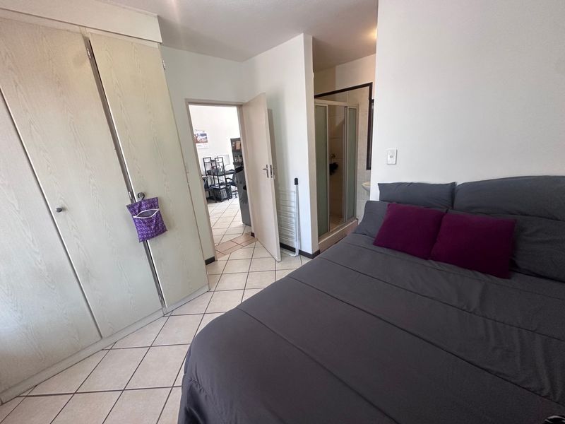 Bedroom featuring built-in cupboards, tiled flooring, and an adjoining en-suite shower room.