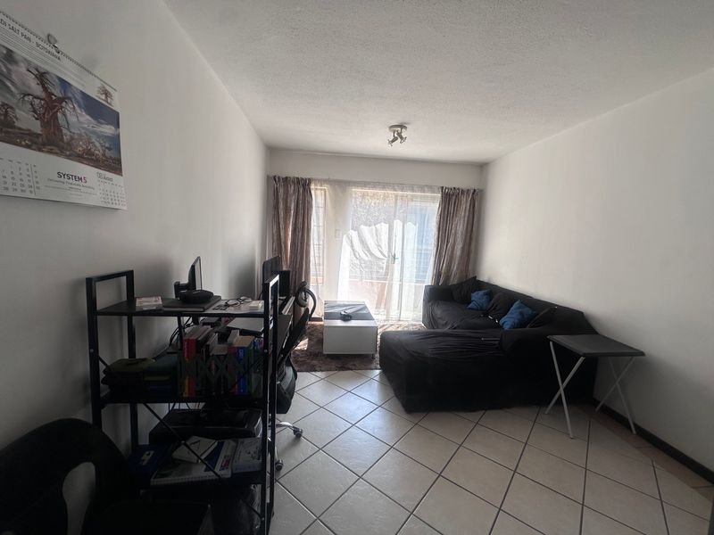 A living room featuring tiled flooring and a sliding glass door providing access to an outdoor area.