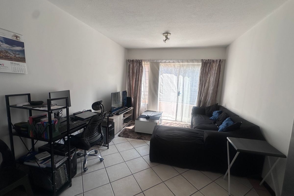 A functional living room featuring tiled flooring and a sliding glass door providing natural light and access to the exterior.
