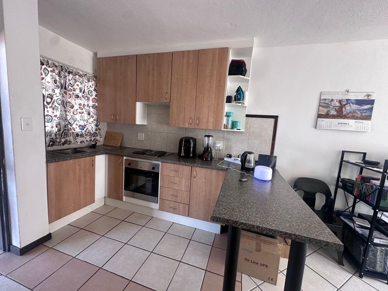 Functional kitchen featuring wood-look cabinetry, laminate countertops, a breakfast bar, built-in oven, and ceramic floor tiling.