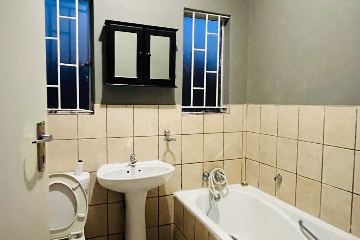 A functional bathroom featuring a pedestal basin, bathtub, and tiled finishes, offering a clean space with potential for modern updates.