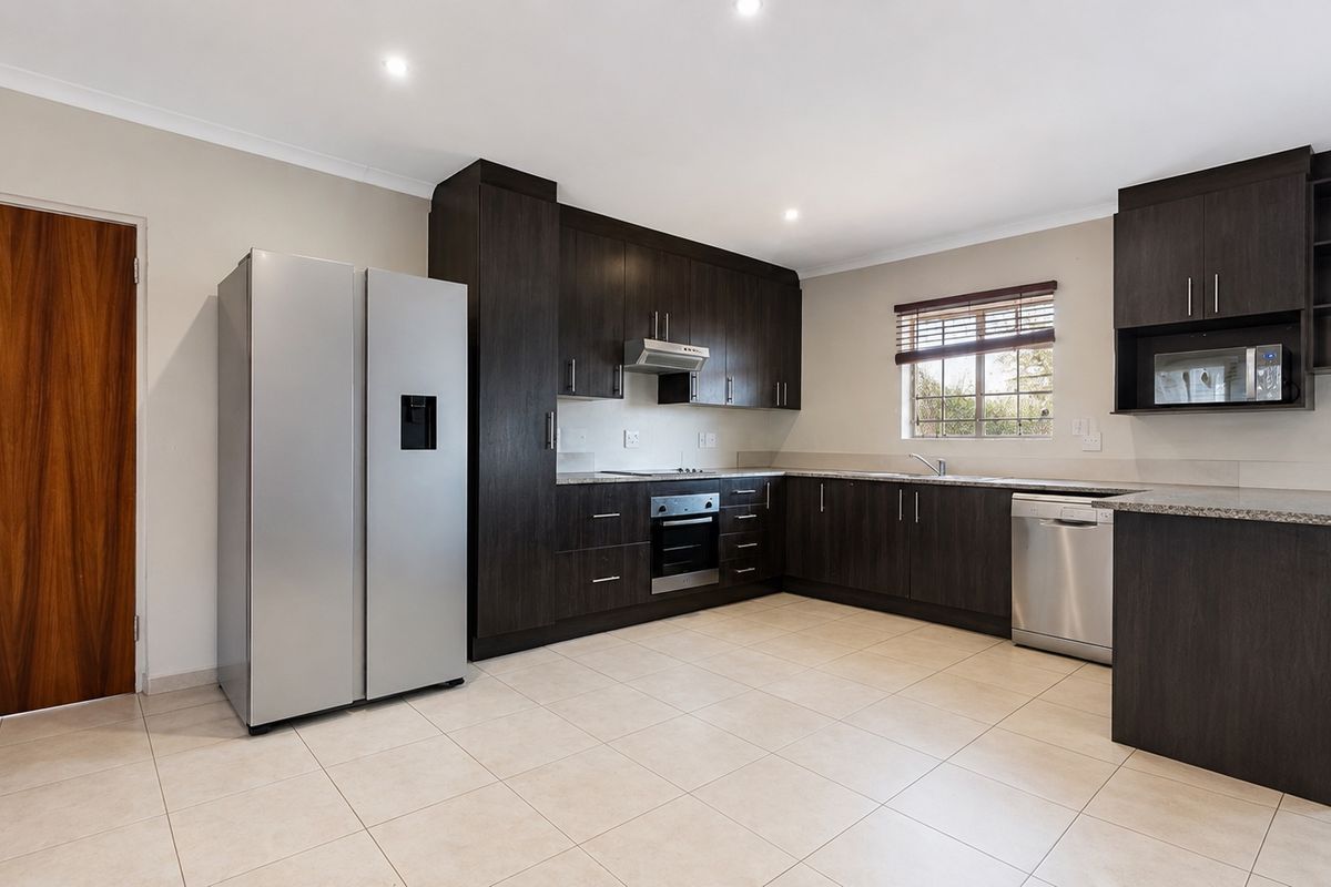 Modern kitchen featuring dark wood cabinetry, granite countertops, built-in oven, extractor fan, and tiled flooring in a clean, well-maintained space.