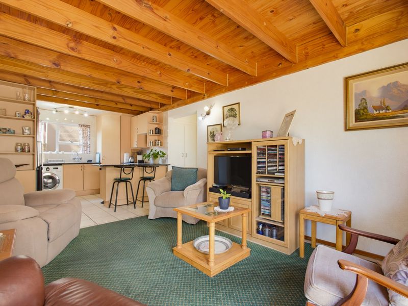 Open-plan living and kitchen area featuring exposed timber beam ceilings, a breakfast bar, and a functional kitchen layout with integrated cabinetry.