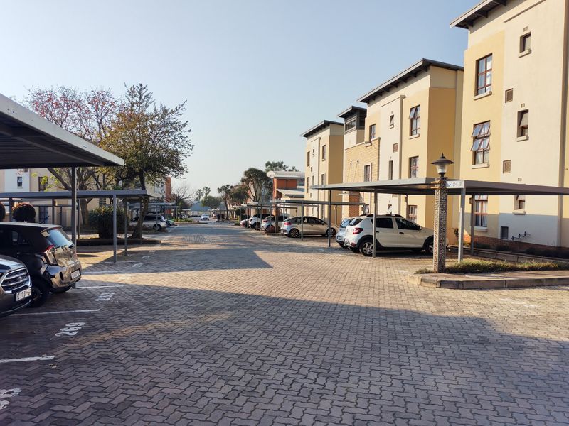 Exterior view of an apartment complex featuring paved parking areas with covered carports and multi-story residential building facades.
