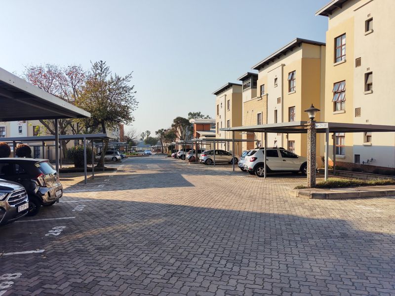 Exterior view of an apartment complex featuring paved parking areas and covered carport structures for residents.