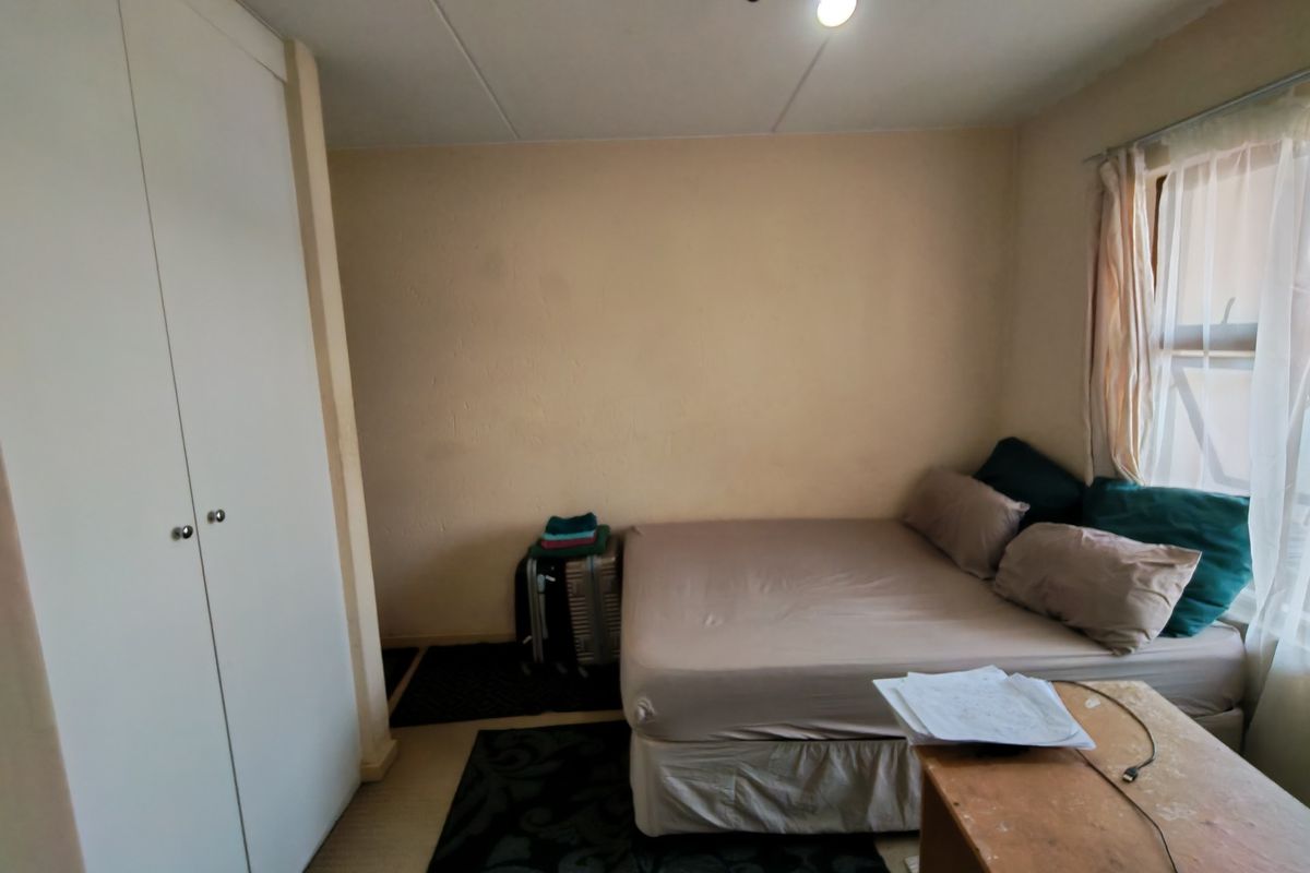 A compact bedroom featuring a built-in wardrobe and neutral wall finishes, offering a functional space ready for cosmetic updates.
