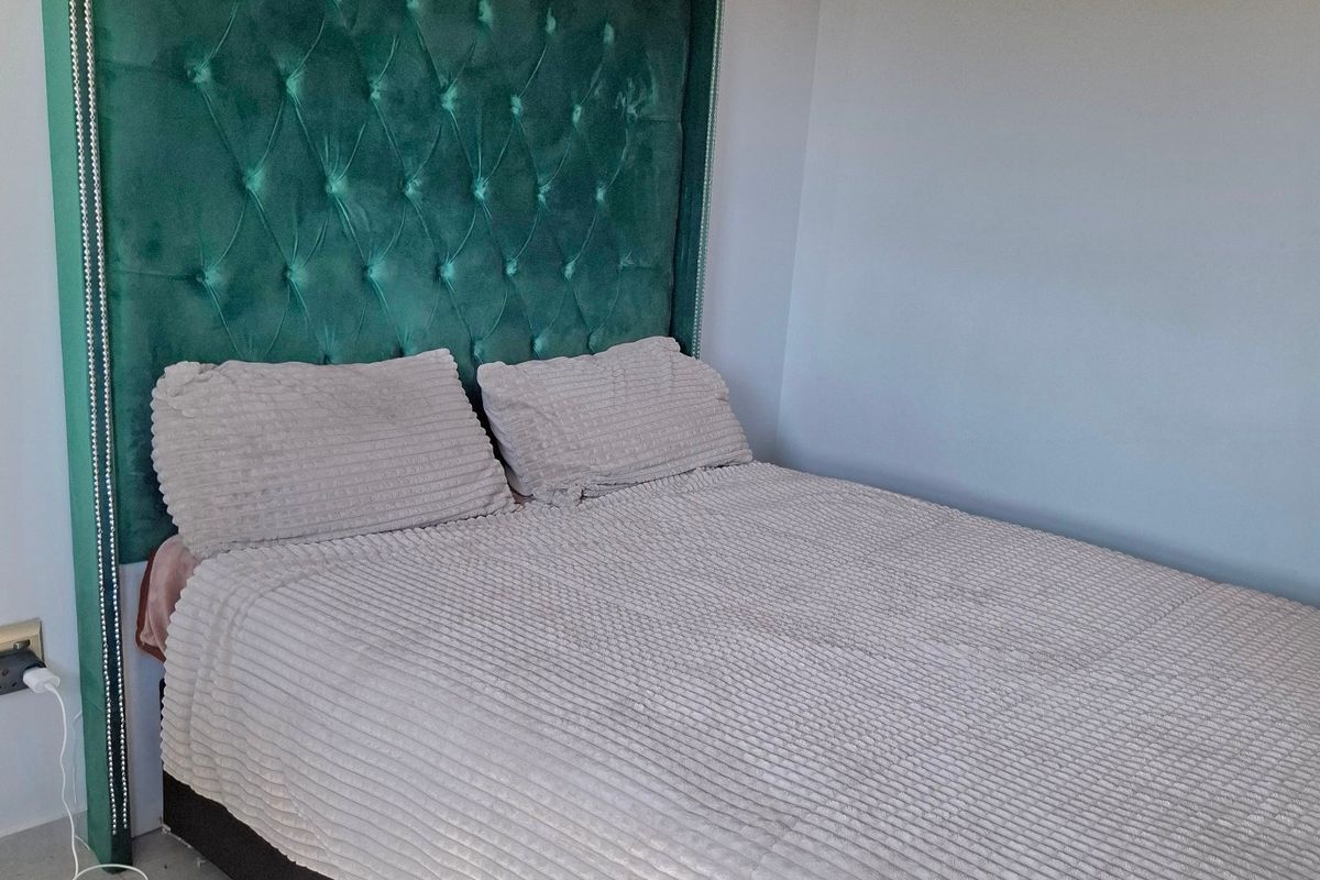 A well-maintained bedroom featuring neutral tiled flooring and clean wall finishes, providing a simple and functional sleeping space.