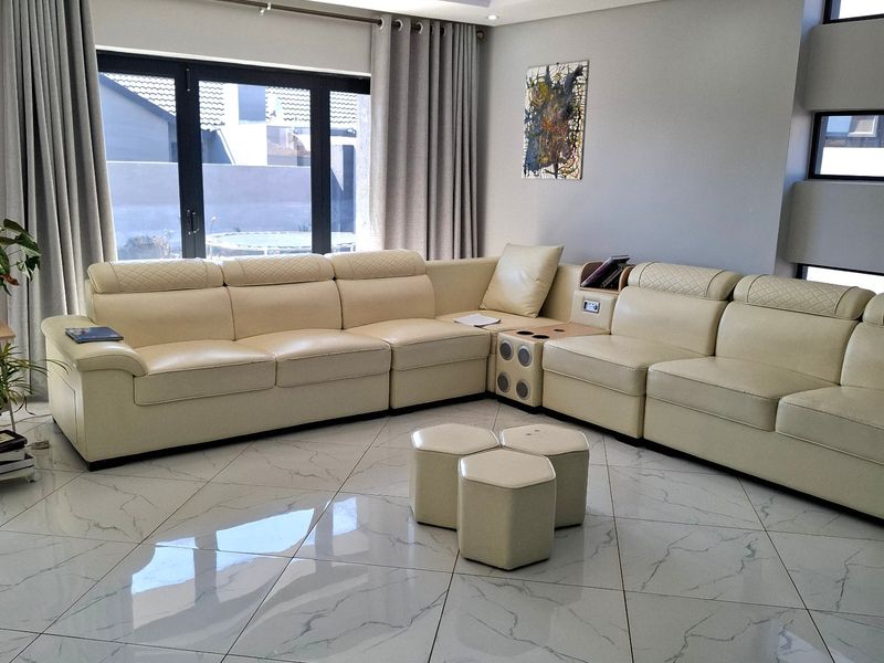 Modern living room featuring high-gloss marble-look floor tiles, recessed ceiling lighting with blue accent cove lighting, and large aluminium sliding doors.