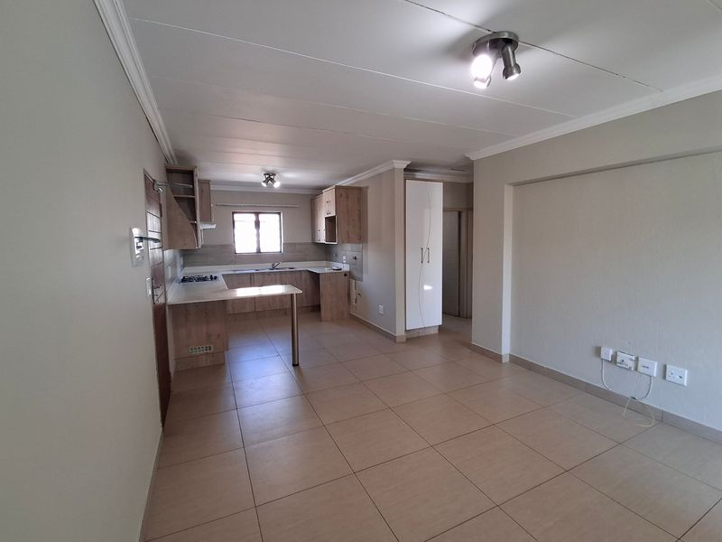 Spacious open-plan living and kitchen area featuring tiled floors, modern light-toned cabinetry, a gas hob, and a built-in storage cupboard.