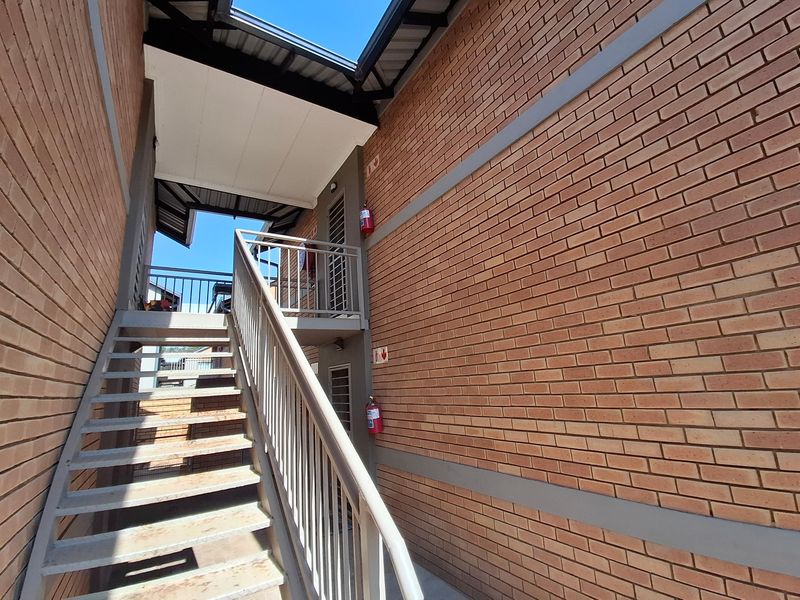 Exterior view of a townhouse complex featuring a metal staircase, brick facade, and safety fire equipment.