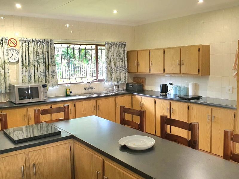 A functional kitchen featuring extensive wooden cabinetry, laminate countertops, a double sink, and a built-in oven with a tiled backsplash.