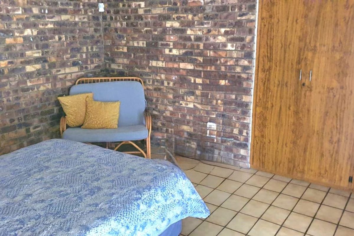 A bedroom featuring an exposed brick feature wall, tiled flooring, and built-in wooden wardrobe storage.