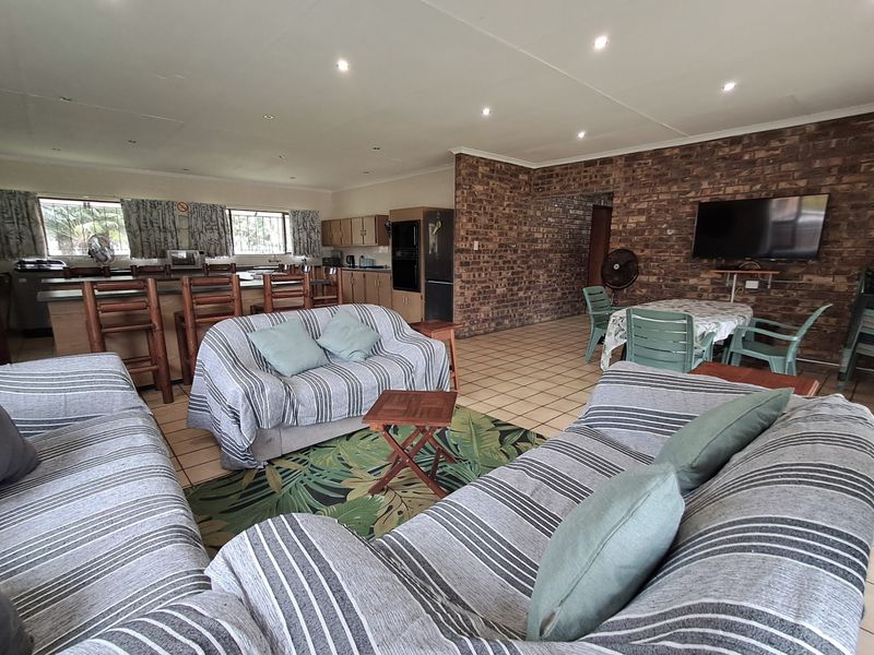 Spacious open-plan living and kitchen area featuring exposed brick feature walls, tiled flooring, and a functional breakfast bar layout.