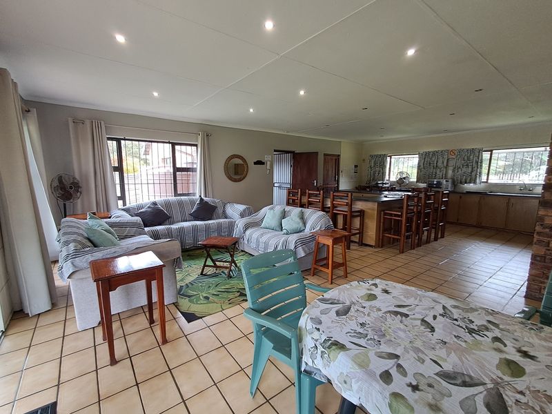 Spacious open-plan living and kitchen area featuring tiled flooring, recessed lighting, and a central kitchen island, offering a functional and versatile layout.