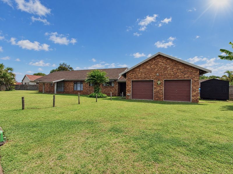 A well-maintained single-story face brick house featuring a double garage, tiled roof, and a spacious front lawn.