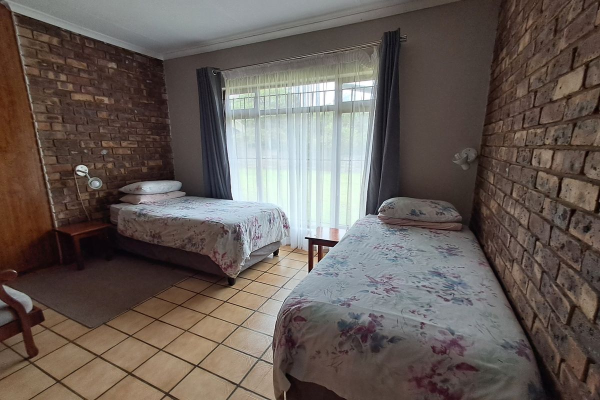 A bedroom featuring exposed brick feature walls, tiled flooring, and a large window allowing natural light.