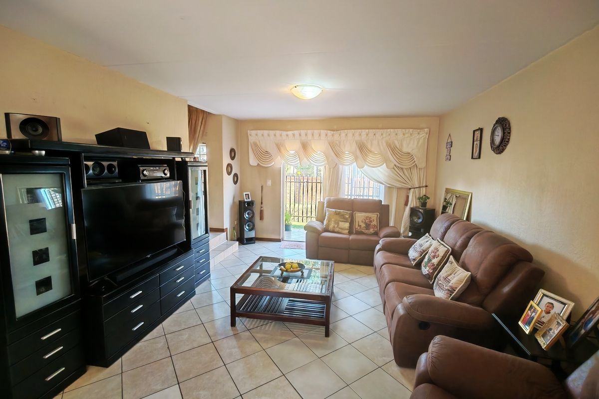 A spacious living room featuring ceramic floor tiles and a sliding glass door providing access to the outdoor area.