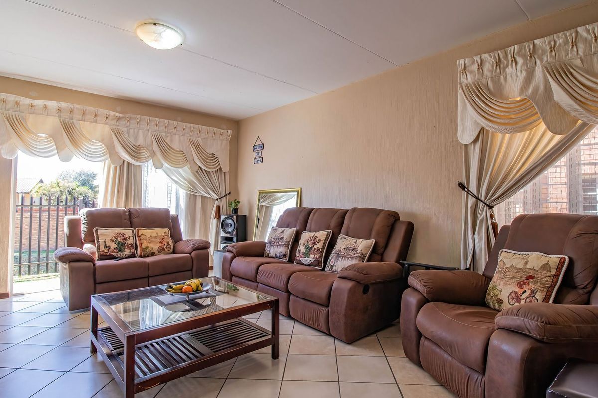 A spacious living room featuring tiled flooring and a large sliding glass door providing access to the exterior.